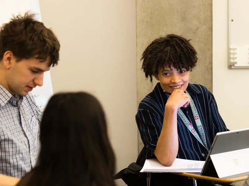 3 students talking in a seminar, 1 smiling 