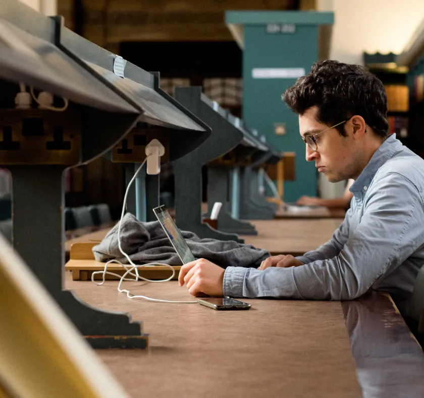 researcher reading at long readers' desk in the University Library