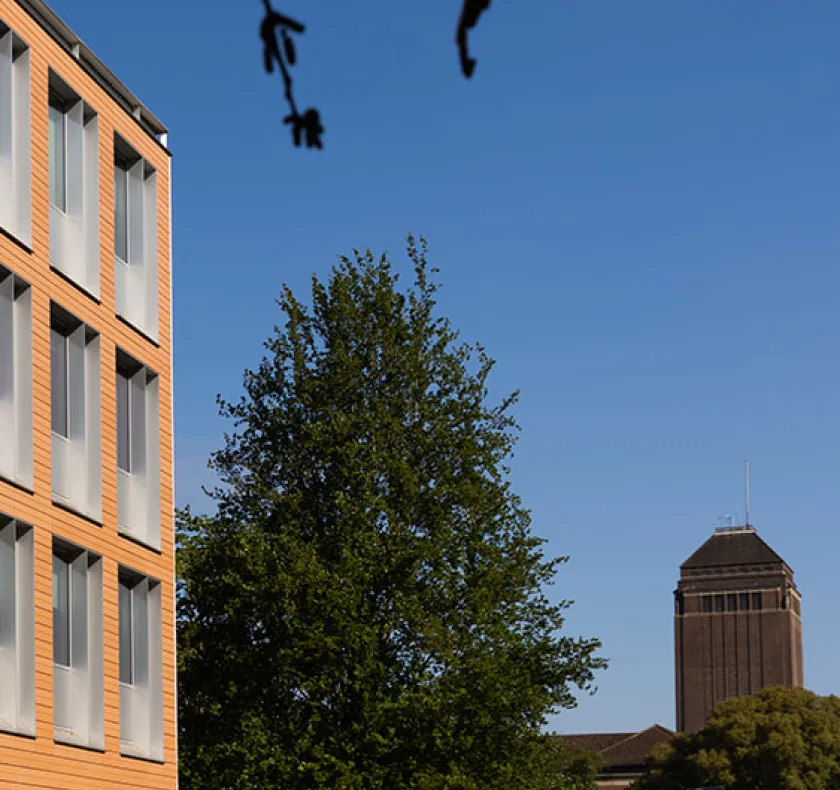 Sunlit terraccota Faculty building with University Library tower in the backgroun