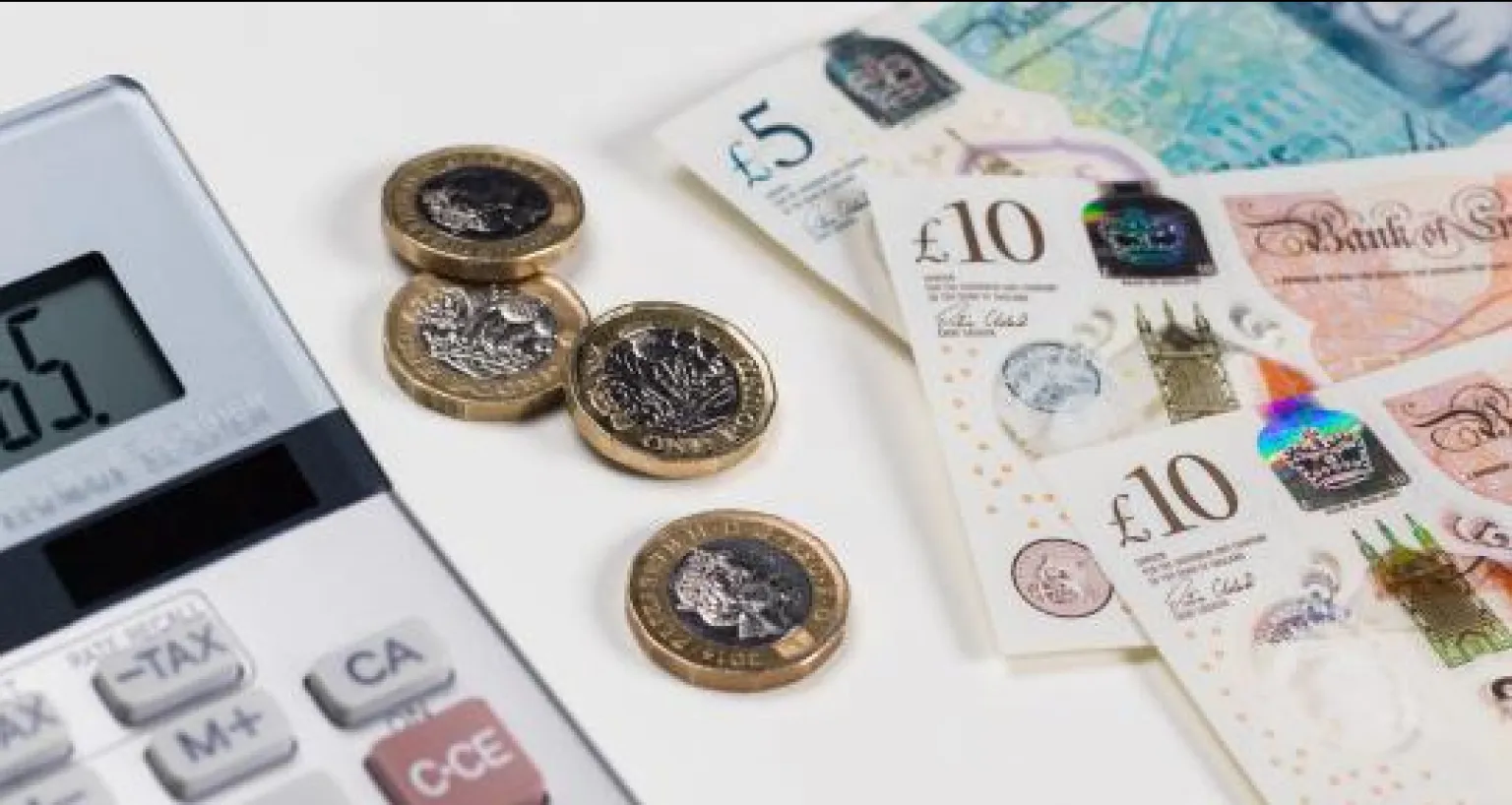 a calculator with coins and notes beside it