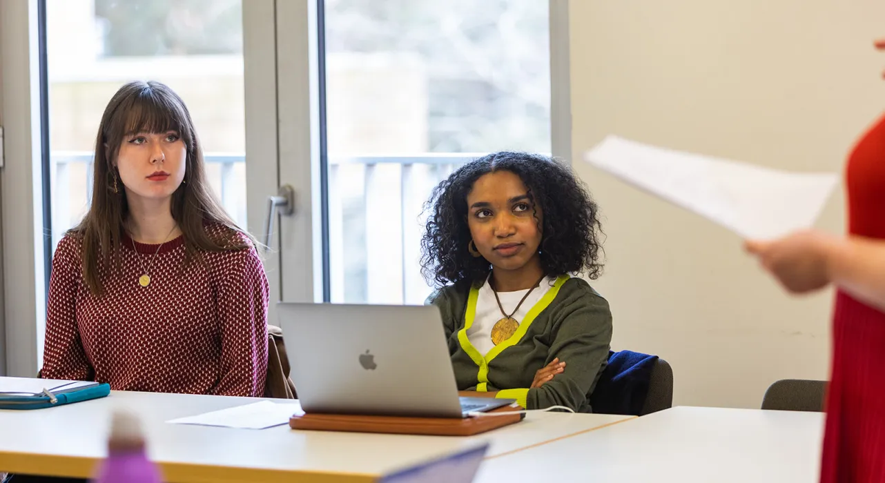 two students sitting, listening to lecturer