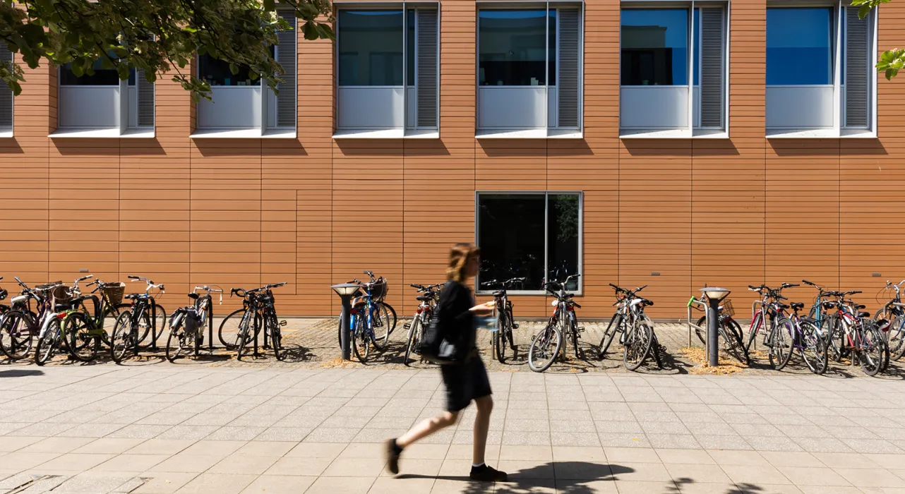 person walking past Faculty building on sunny day