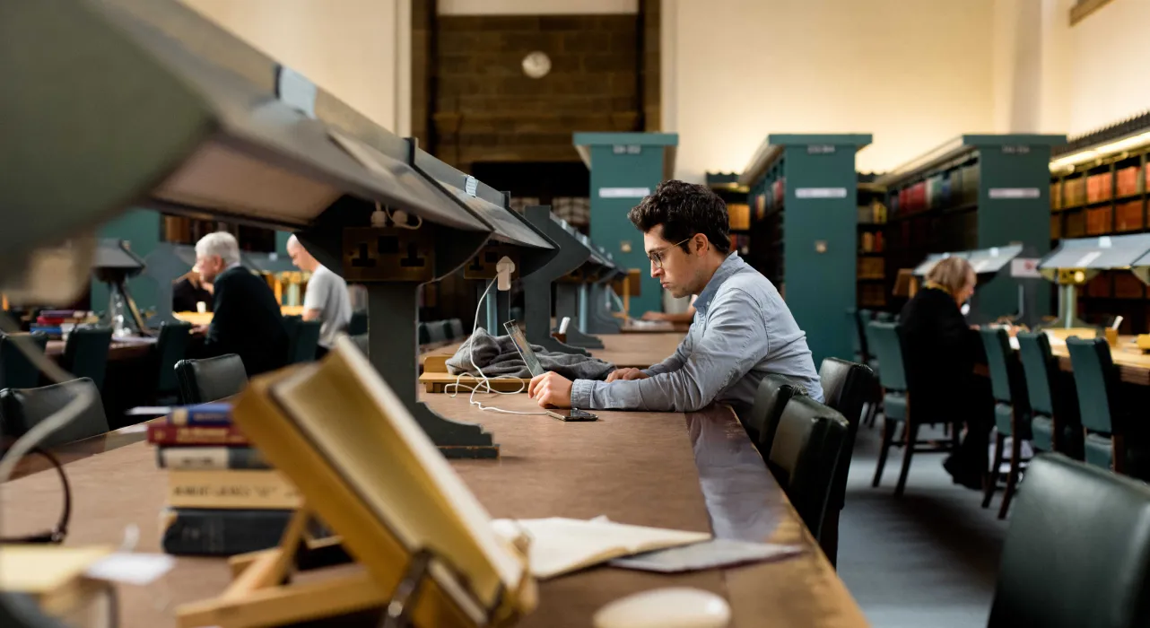 researcher reading at long readers' desk in the University Library