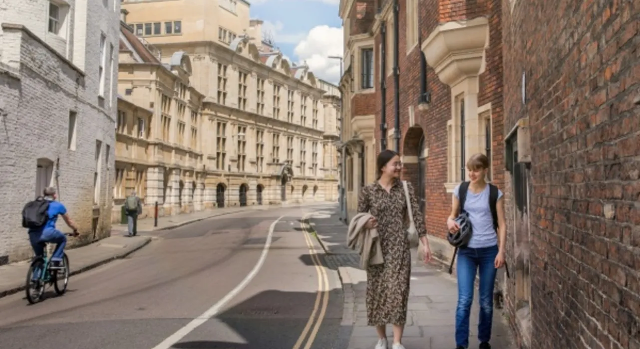 students walking down a street in Cambridge with historical buildings in background