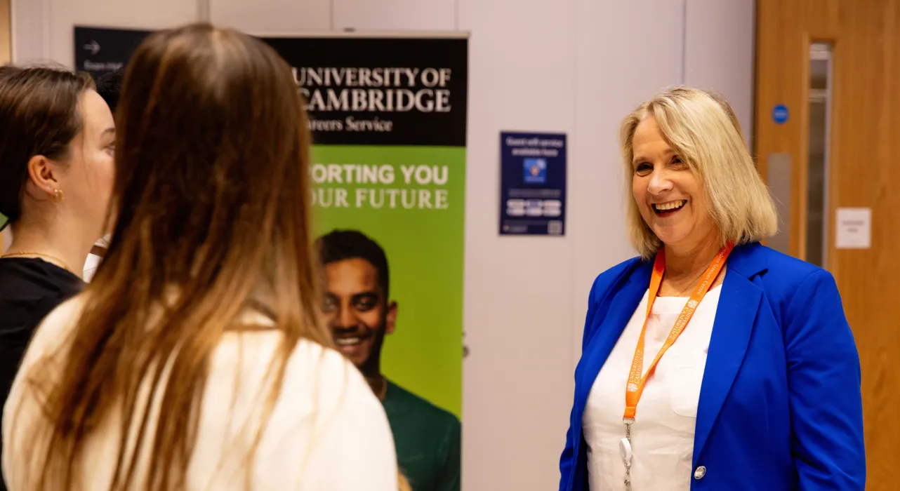 Three University staff members are talking in front of a banner at the Student Services Careers Centre. Copyright: University of Cambridge (November 2024)