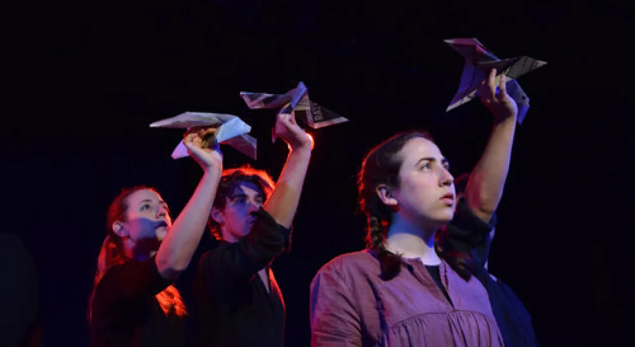 three figures staring into the sky, holding paper airplanes above their heads