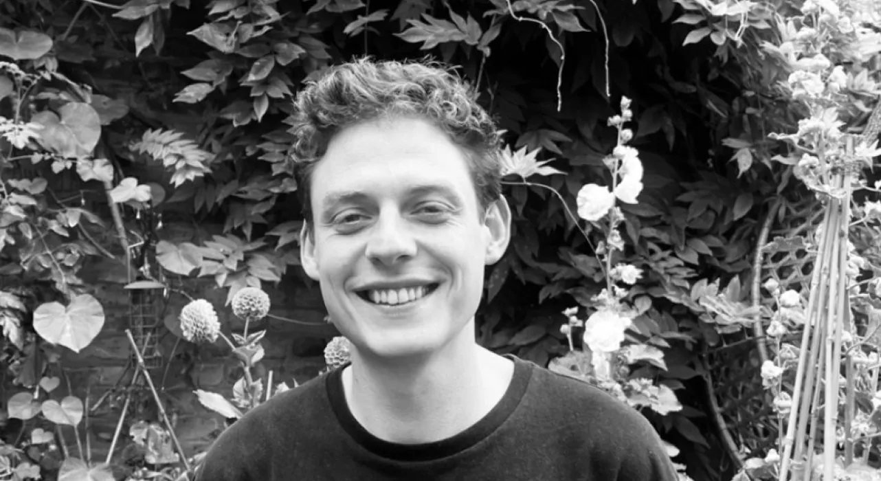 A man wearing a dark jumper and smiling at the camera.