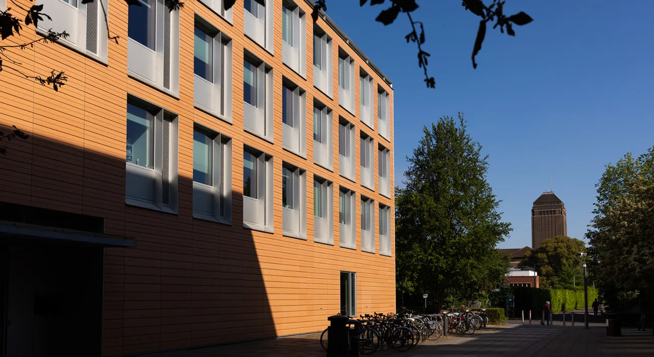 Sunlit terraccota Faculty building with University Library tower in the backgroun