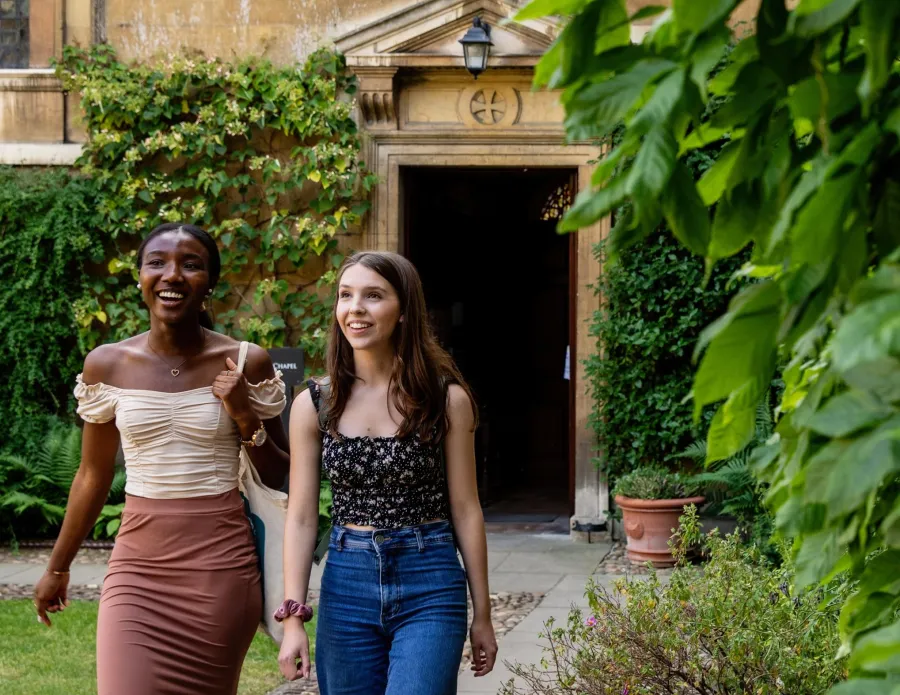 Two University of Cambridge students walking and talking at Trinity Hall. Copyright: University of Cambridge (June 2023)