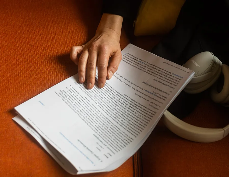 close up of a hand resting on a document, with a pair of headphones nearby