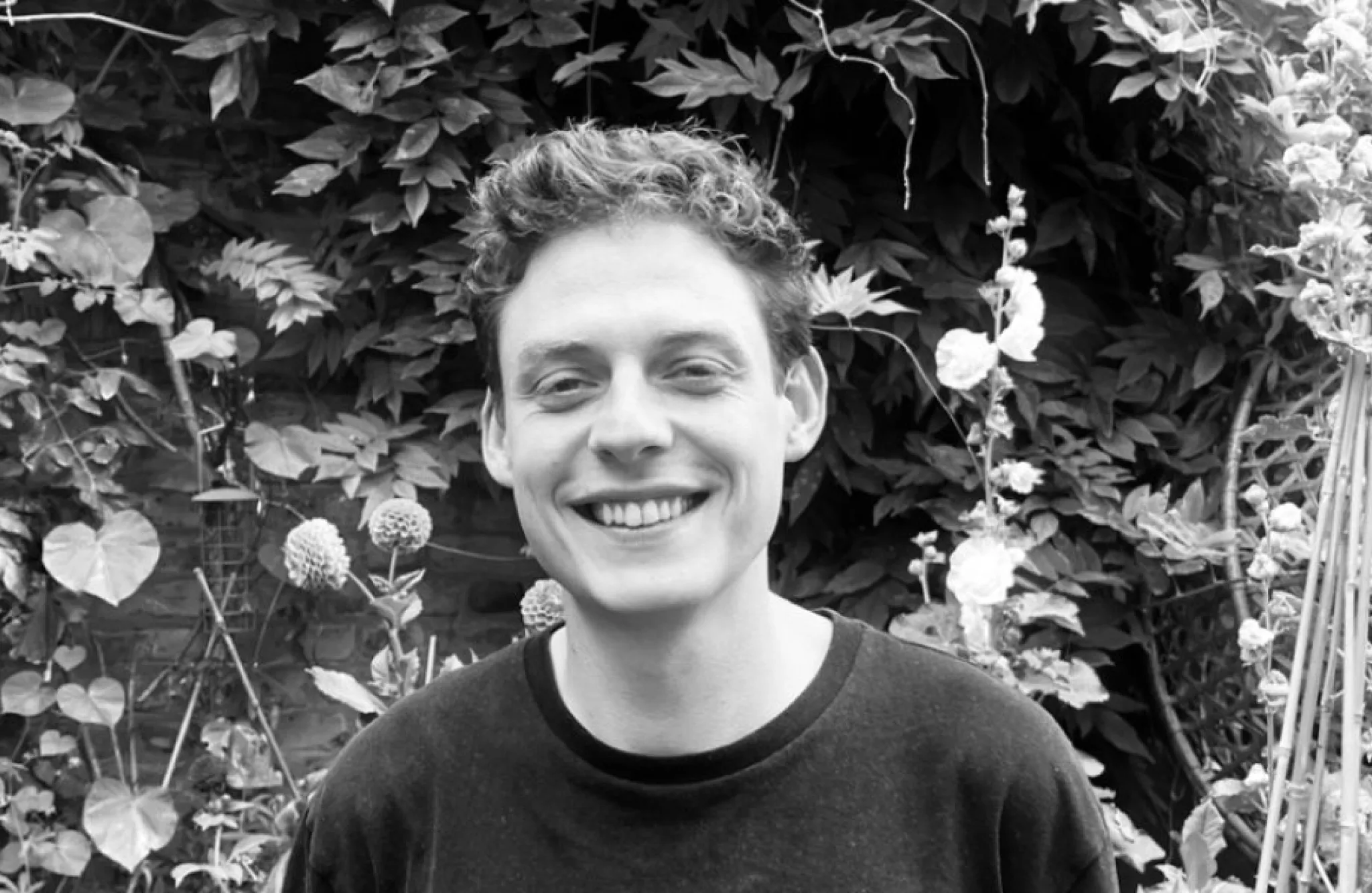 A man wearing a dark jumper and smiling at the camera.
