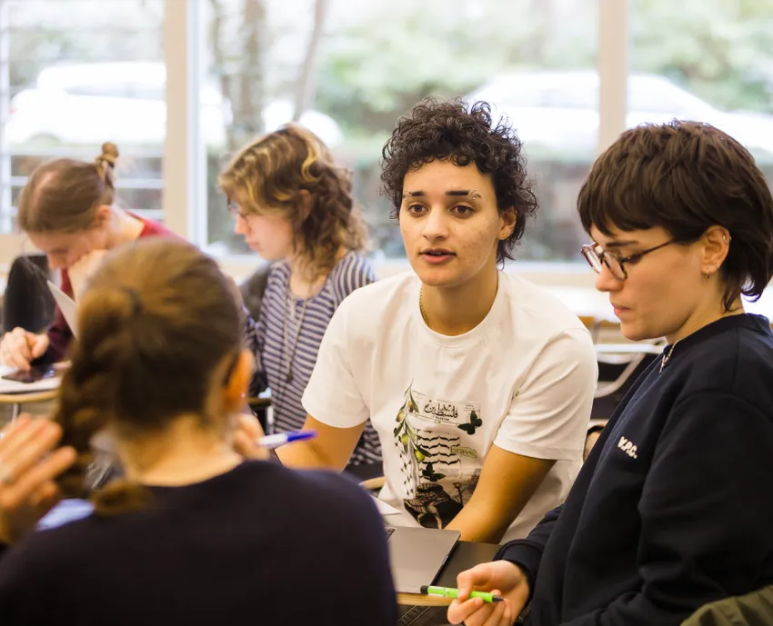 three students in discussion, two more in pair behind