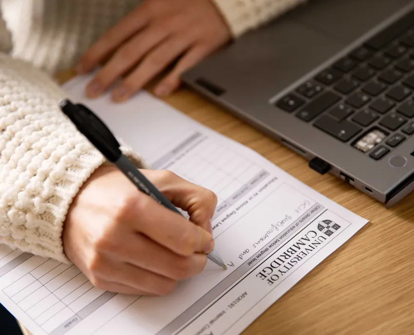 A University staff member working and writing on a paper form at the Old Cavendish Copyright: University of Cambridge (November 2024)